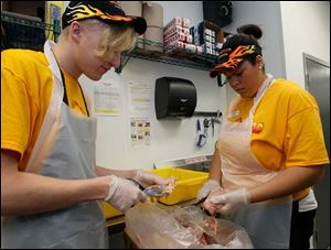 On their second day of work at Hot Head Burritos in Perrysburg, Jake Renner, 19, of Holland, left, and Jordan Williams, 21, of Lyons, Ohio, prepare chicken.