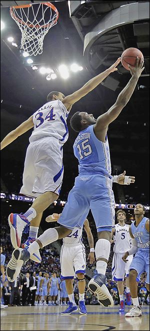 North Carolina’s P.J. Hairston, right, shoots under pressure from Kansas’ Perry Ellis during the first half. The top-seeded Jayhawks over came a sluggish start to pick up the 70-58 victory.