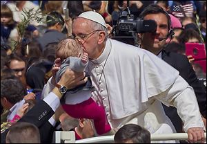Pope Francis kisses a baby after celebrating his first Palm Sunday Mass in St. Peter's Square at the Vatican on Sunday.