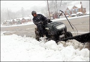 Bobby Jones of Bel-Ridge, Mo., near St.Louis, clears the parking lane in front of his North Hanley Road home with his lawn tractor on Sunday, as a new blanket of wintry weather hits the St. Louis region early in Spring. 
