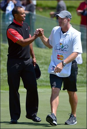 Tiger Woods, left, is congratulated by caddie Joe LaCava on the 18th green after winning the Arnold Palmer Invitational golf tournament in Orlando, Fla.