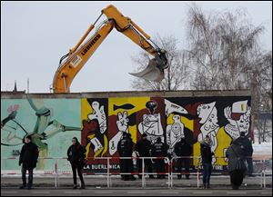 Police officers guard a construction site and sections of the East Side Gallery, while parts of the former Berlin Wall are removed in Berlin, Germany.