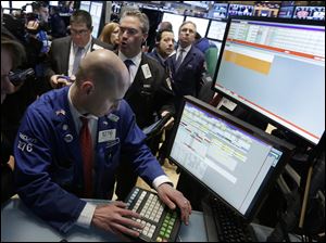Specialist Mario Picone, left, works with traders at his post on the floor of the New York Stock Exchange. Renewed jitters about Europe's debt crisis sent world stock markets lower today.