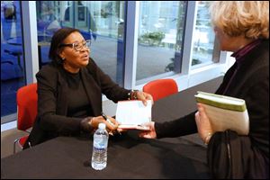Author and guest speaker Jamaica Kincaid chats with Susan Haley of South Toledo, right, while signing books at the Main Library in downtown Toledo.