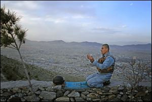 An Afghan police officer offers evening prayers with Kabul, Afghanistan, in the background. Afghan President Hamid Karzai held talks Sunday with the emir of Qatar during a visit to discuss a Taliban presence in Qatar.