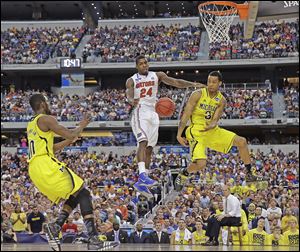 Michigan's Trey Burke (3) passes the ball to Tim Hardaway, Jr., in front of Florida's Casey Prather for an easy dunk in the second half. The Wolverines  (30-7) will play Syracuse (30-9) in the Final Four on Saturday night in Atlanta.