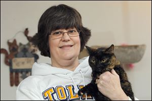 Jill Falls of Sylvania Township holds Monkey, who, along with Ms. Falls’ other cats, has experienced dental problems.