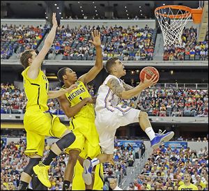 Florida's Scottie Wilbekin tries to get off a shot as Michigan's Glenn Robinson III (1) and Nik Stauskas defend during the first half in Arlington, Texas. Wilbekin finished with four points for the Gators.