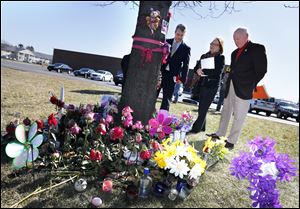 Progress Ohio's Brian Rothenberg, left, Toby Hoover from the Ohio Coalition Against Gun Violence, and former Toledo Mayor Carty Finkbeiner, right, pause at a memorial site for Kaitlin Gerber.