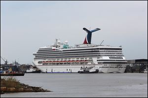 Tug boats maneuver around the Carnival cruise ship Triumph as it rests against a dock on the east side of the Mobile River after becoming dislodged from its mooring at BAE Shipyard during high winds Wednesday, April 3, 2013 in Mobile, Ala. 