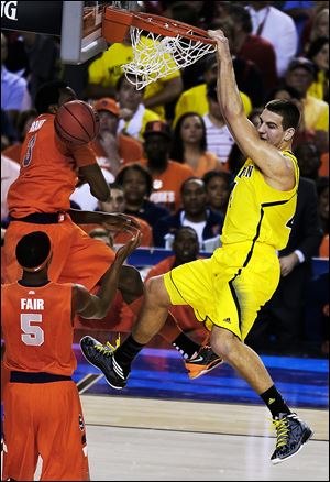 Michigan's Mitch McGary dunks the ball against Syracuse's Jerami Grant (3) and C.J. Fair during the first half. McGary also had a pair of blocks early in the Final Four contest in the Georgia Dome in Atlanta on Saturday evening.