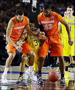 Syracuse's Michael Carter-Williams (1) and James Southerland (43) vie for a loose ball Michigan's Trey Burke during the first half.