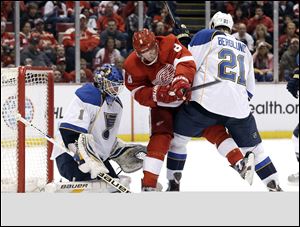 St. Louis Blues center Patrik Berglund (21), of Sweden, defends Detroit Red Wings left wing Justin Abdelkader (8) in front of goalie Brian Elliott (1) in the second period of an NHL hockey game in Detroit, Sunday April 7, 2013. (AP Photo/Paul Sancya)  