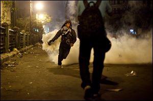 A protester throws away a tear gas canister fired by security forces in downtown Cairo, Egypt, Saturday.