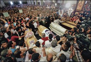 Coptic Christians gather around four coffins during a funeral service Sunday at St. Mark’s Coptic Orthodox Cathedral in Cairo. Violence after the funeral for the four Christians who were killed Friday led to another person dead and 84 injured.