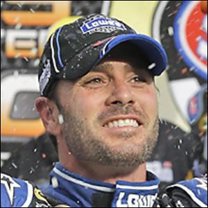 An official waits to hand  Jimmie Johnson the checkered flag after winning the race at Martinsville Speedway on Sunday. It was the eighth time he has won at the track, third-best among all drivers.