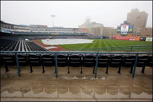 Seats are reflected in standing water and a tarp covers the playing surface Wednesday at Fifth Third Field. Weather permitting, the Mud Hens will play their home opener today against Louisville.