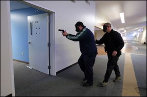 Sgt. Doug Perry, left, of the University of Toledo Police Department, heads into a hallway as instructor trainer candidate Frank Chickos of the Bainbridge Township Police Department follows during a training scenario.