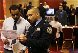 In this Tuesday, Feb. 26, 2013, photo, Philadelphia police recruiting officer Samuel Cruz, right, talks with Ismail Azeer of Carteret, N.J., at the Edison Career Fair job fair in the Iselin section of Woodbridge Township, N.J. The number of Americans seeking U.S. unemployment benefits fell sharply last week to a seasonally adjusted 346,000, suggesting March's weak month of hiring may be a temporary slowdown. Employers added only 88,000 jobs in March after averaging 220,000 the previous four months. The drop in unemployment benefits suggests hiring could pick up again in April. (AP Photo/Mel Evans)