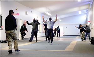 During an active-shooter training scenario, a responding officer, left, arrives at the scene of a shooting as others portraying victims flee in chaotic fashion, creating noise and confusion. The officer has to apply his classroom training to handle the situation.