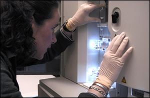 In this image provided by the National Human Genome Research Institute, a NHGRI researcher monitors a DNA sequencing machine at the NIH in Bethesda, Md. 