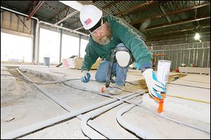 Tim Rank of Willson Builders in Toledo marks a floor before pinning concrete together as he and other company workers build an Art Van PureSleep store at Talmadge Road and Monroe Street.