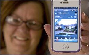 Donna Chapman opens the Redfin app on her iPhone and shows off the sold sign banner attached to a photo of her new home in Corona, California.