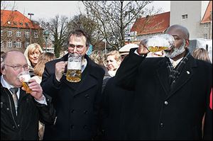 Toledo Mayor Mike Bell, right, and Patrick de La Lanne, center, mayor of Delmenhorst, Germany, celebrate a yearly spring festival with a mug of beer.