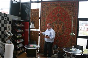 Mark Schroeder of the University of Toledo looks at pieces of linoleum in the Nordwolle museum. Behind him is a piece of linoleum that resembles a tapestry.