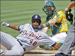 The Tigers' Torii Hunter slides in safely to score past the A’s Derek Norris in the first inning. Hunter scored on a single by Victor Martinez to open up the floodgates in a 10-1 Tigers victory.