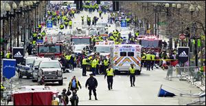 Police clear the area at the finish line of the Boston Marathon as medical workers help injured following explosions today.