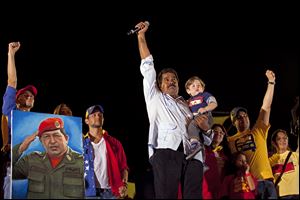 Venezuela’s newly-elected president, Nicolas Maduro, acknowledges the crowd while holding his grandson during his closing campaign rally in Caracas.