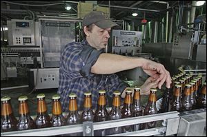 Jeff Kerekes moves beer bottles to the labeling track at the Maumee Bay Brewing Co.
