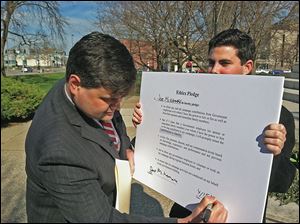 Joe McNamara, left, with campaign aide Andrew Grun-wald, signs an ethics pledge that calls on officials who supervise employees to ban them from campaigning for their bosses during normal business hours.