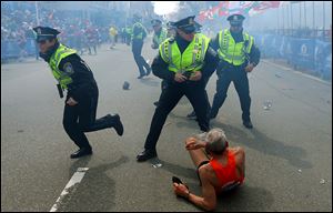 Bill Iffrig, 78, lies on the ground as police officers react to a second explosion at the finish line of the Boston Marathon in Boston, Monday. Iffrig, of Lake Stevens, Wash., was running his third Boston Marathon and near the finish line when he was knocked down by one of two bomb blasts.