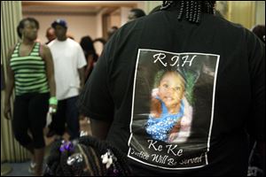 A photo of Keondra Hooks, 1, is on the back of a mourner during the funeral  last August for the little girl who died after being shot inside Moody Manor.
