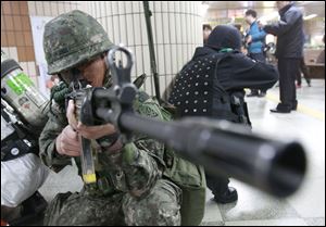 A South Korean army soldier aims his machine gun during an anti-terrorism drill against possible terrorists' attacks at a subway station in Seoul, South Korea, Monday.