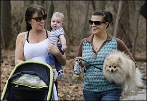 Tina Gray, left, with her grandson, Lincoln Marx, 4 months, and her daughter, Ashley Narewski, walk the trails of Wildwood Preserve Metropark in West Toledo with Ms. Narewski's dog, Cocoa.