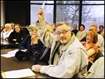  During a meeting on city plans to cut down 120 trees, Dan Markiewicz holds up a postcard that someone put on his yard sign at his home on Cherrylawn Drive.