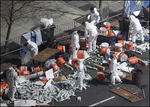 Investigators comb through the post-finish line area of the Boston Marathon at Boylston Street, two days after two bombs exploded just before the finish line.