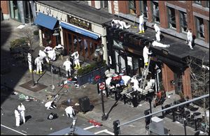 Investigators comb through the scene of one of the blast sites of the Boston Marathon explosions.