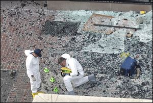 Two men in hazardous materials suits put numbers on the shattered glass and debris as they investigated the scene Tuesday at the first bombing on Boylston Street in Boston.