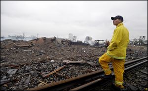 A firefighter stands on a rail line and surveys the remains of a fertilizer plant destroyed by an explosion in West, Texas, today.