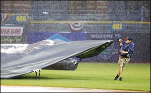 A member of the Toledo Mud Hens grounds crew pulls the tarp to cover the field as play is called during the top of the fifth inning.