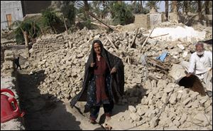 Pakistani villagers pause while collecting their belongings from a debris of their house collapsed by Tuesday's earthquake in Mashkel, southwestern Baluchistan province, today, in Pakistan.