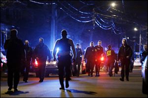 Police officers walk near a crime scene today in a neighborhood in Watertown, Mass. 