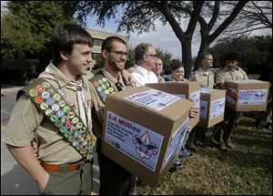 Form a February photo, James Oliver, left, hugs his brother and fellow Eagle Scout, Will Oliver, who is gay, as Will and other supporters carry four boxes filled with a petition to end the ban on gay scouts and leaders in front of the Boy Scouts of America headquarters in Dallas.