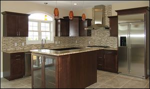 Crown molding tops the kitchen’s maple cabinetry. The island and counters are topped with Santa Cecilia granite.