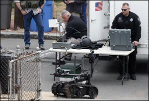 A member of the Cambridge police bomb squad, right, deploys a robot on Norfolk Street during a search for searching a suspect in the Boston Marathon bombings in Cambridge, Mass.. Two suspects in the Boston Marathon bombing killed an MIT police officer, injured a transit officer in a firefight and threw explosive devices at police during a getaway attempt in a long night of violence that left one of them dead and another still at large Friday, authorities said as the manhunt intensified for a young man described as a dangerous terrorist.