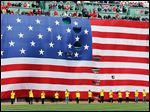  Boston Marathon volunteers stand beneath a giant flag on the outfield wall of Fenway Park during a tribute before a game between the Boston Red Sox and the Kansas City Royals on Saturday.